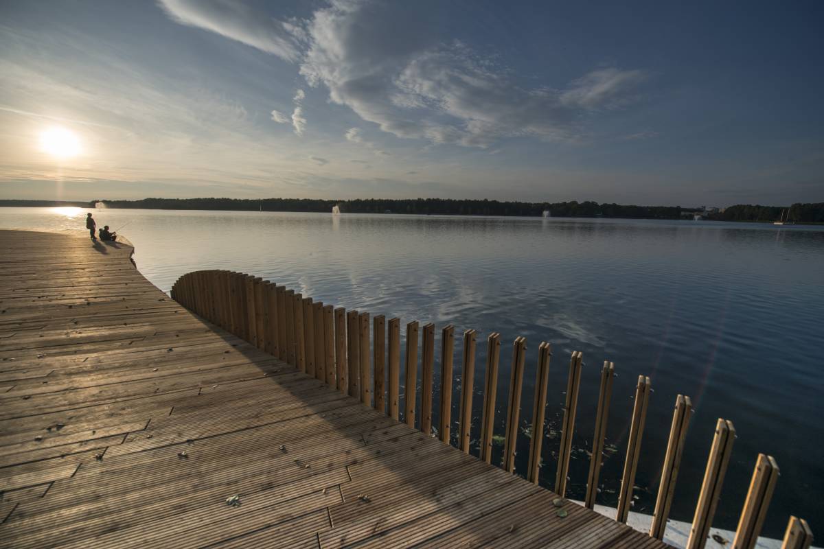 widok na jezioro o zachodzie słońca, na pierwszym planie drewniana promenada